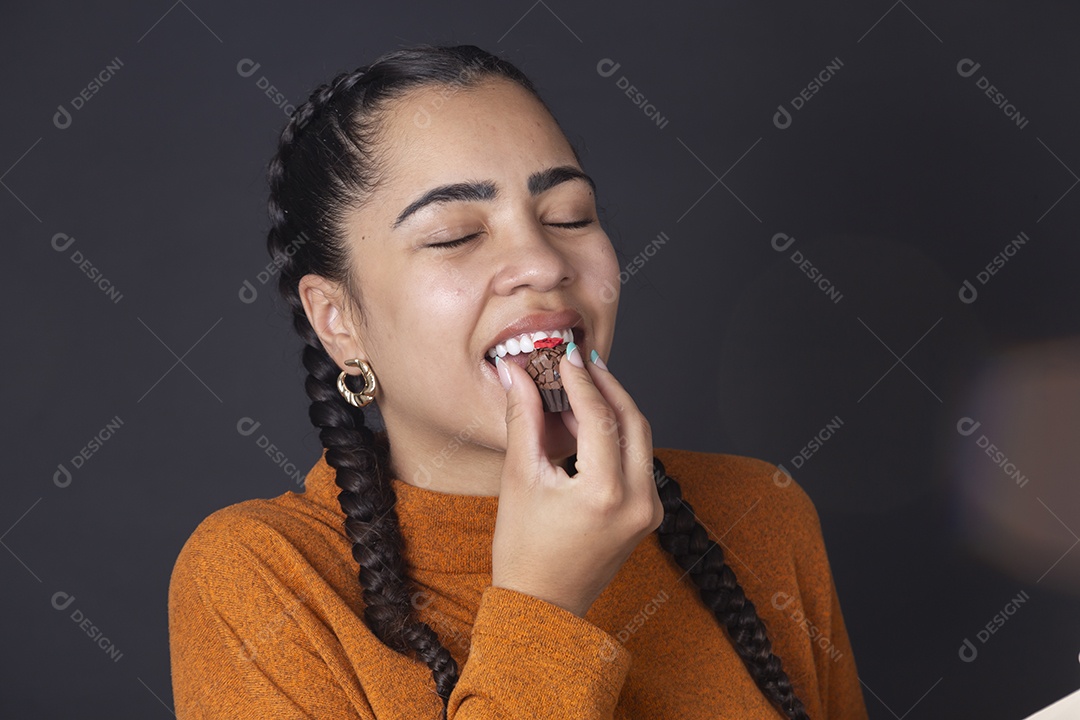 Mulher degustando chocolate sobre fundo escuro