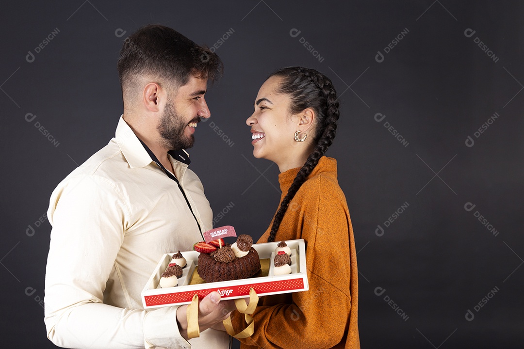 Casal  segurando caixa de doces e sorrindo comemorando dia de dos namorados