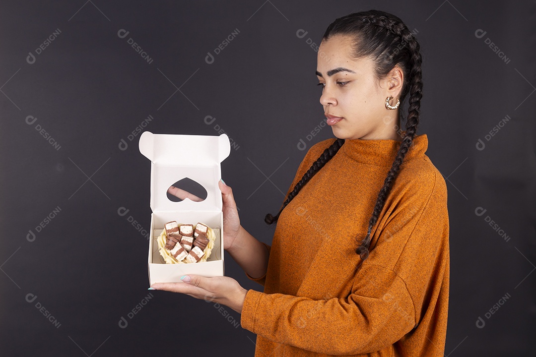 Mulher segurando caixa de chocolate sobre fundo escuro