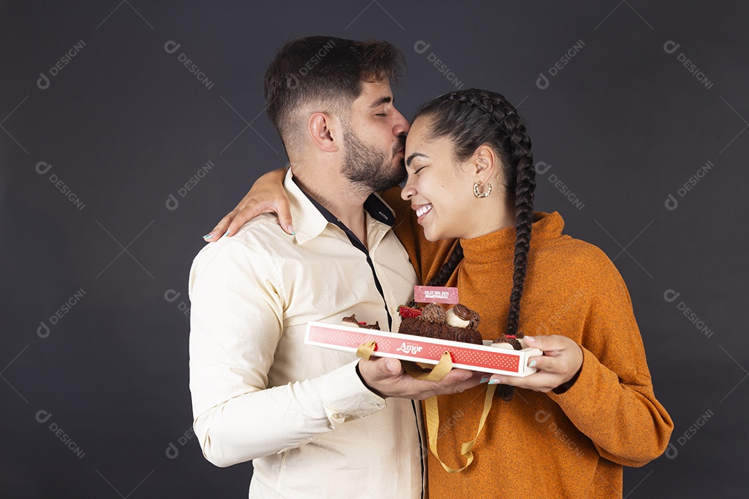 Casal feliz se abraçando e segurando caixa de bolo de juntos