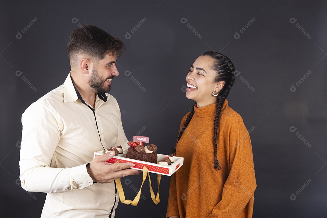 Casal de jovem apaixonados sorrindo e comemorando dia dos namorando com bolo