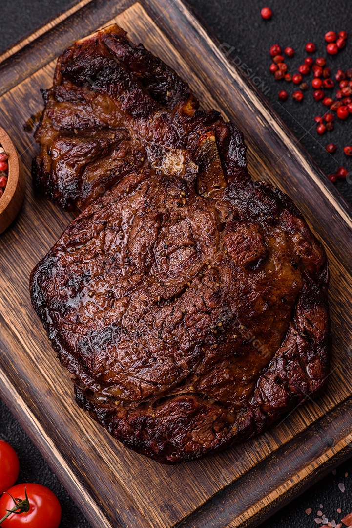 Delicioso bife suculento de lombo grelhado com sal, especiarias e ervas em um fundo escuro de concreto