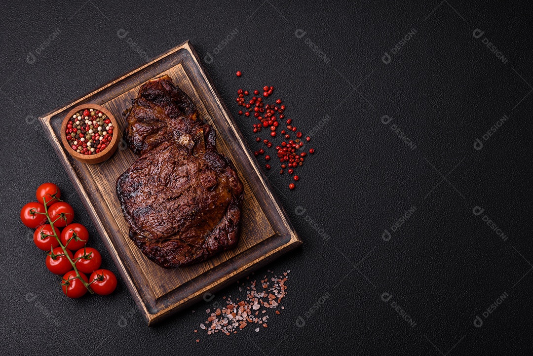 Delicioso bife suculento de lombo grelhado com sal, especiarias e ervas em um fundo escuro de concreto