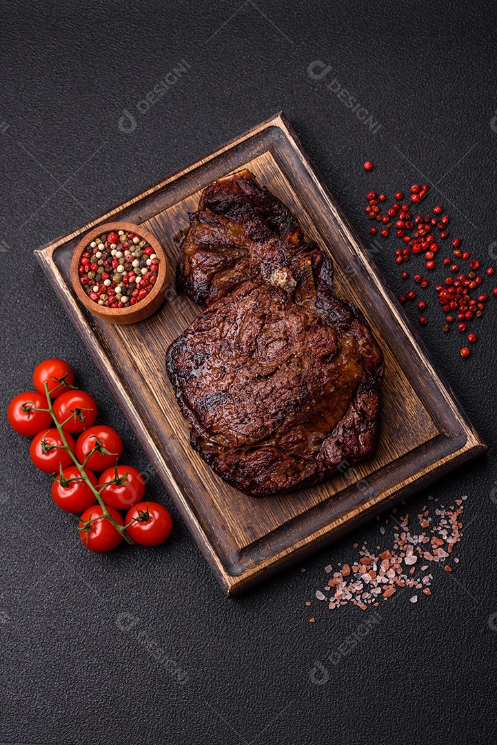 Delicioso bife suculento de lombo grelhado com sal, especiarias e ervas em um fundo escuro de concreto