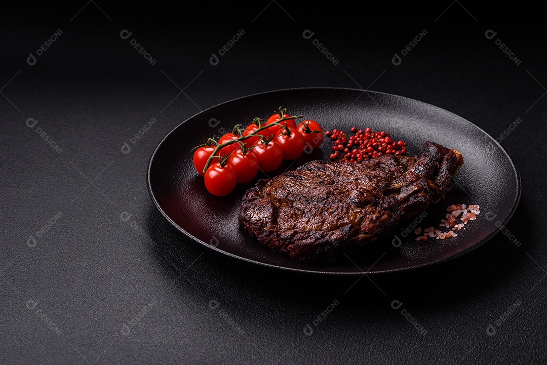 Delicioso bife suculento de lombo grelhado com sal, especiarias e ervas em um fundo escuro de concreto