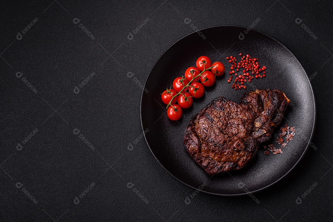 Delicioso bife suculento de lombo grelhado com sal, especiarias e ervas em um fundo escuro de concreto