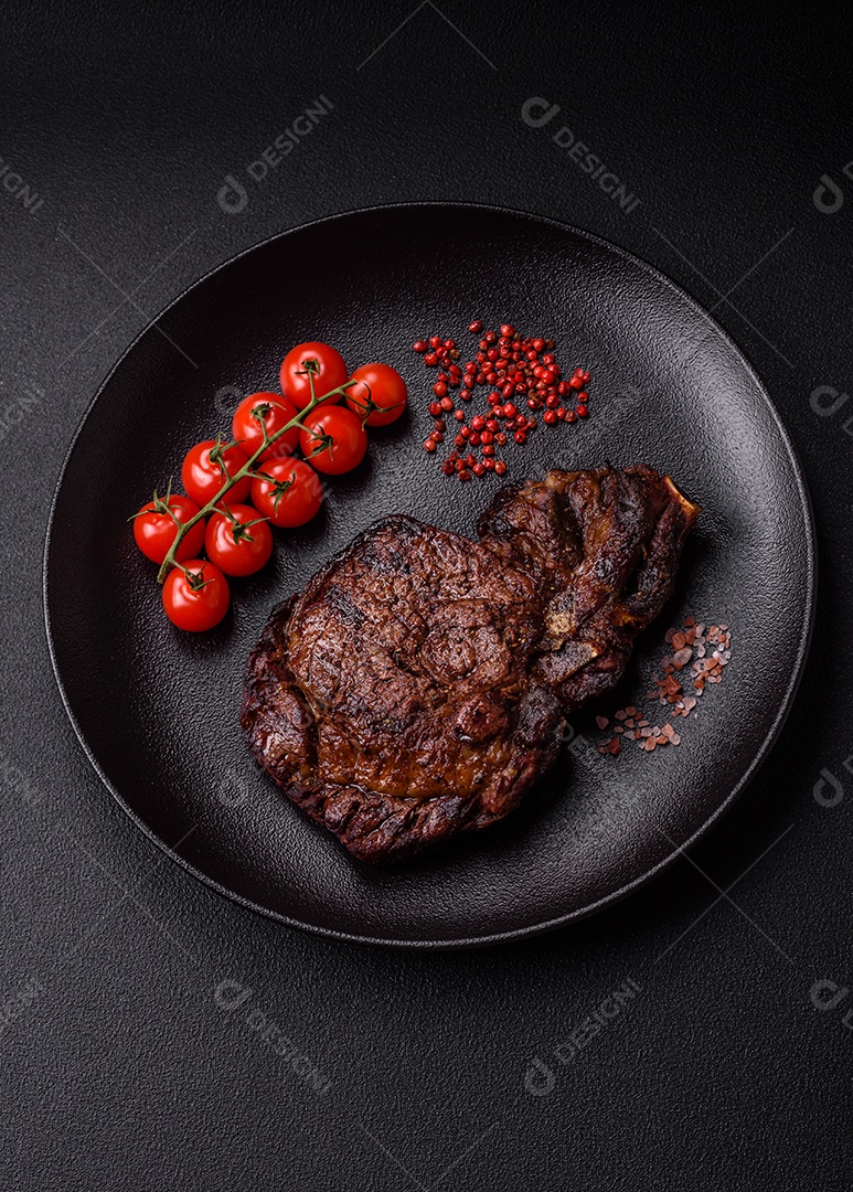 Delicioso bife suculento de lombo grelhado com sal, especiarias e ervas em um fundo escuro de concreto