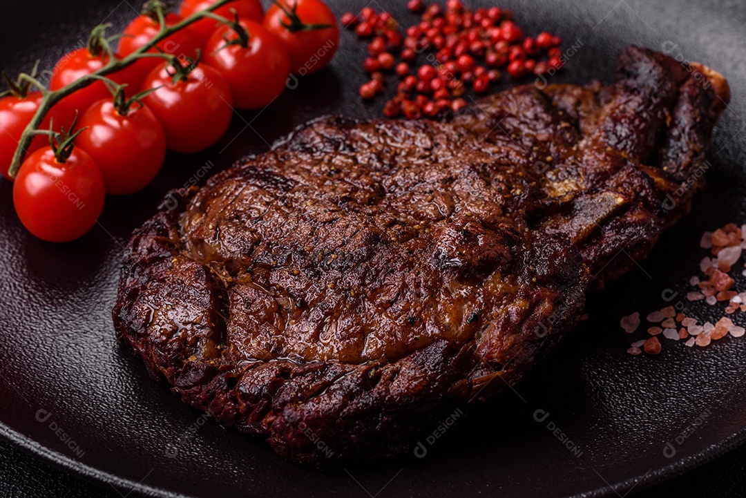 Delicioso bife suculento de lombo grelhado com sal, especiarias e ervas em um fundo escuro de concreto