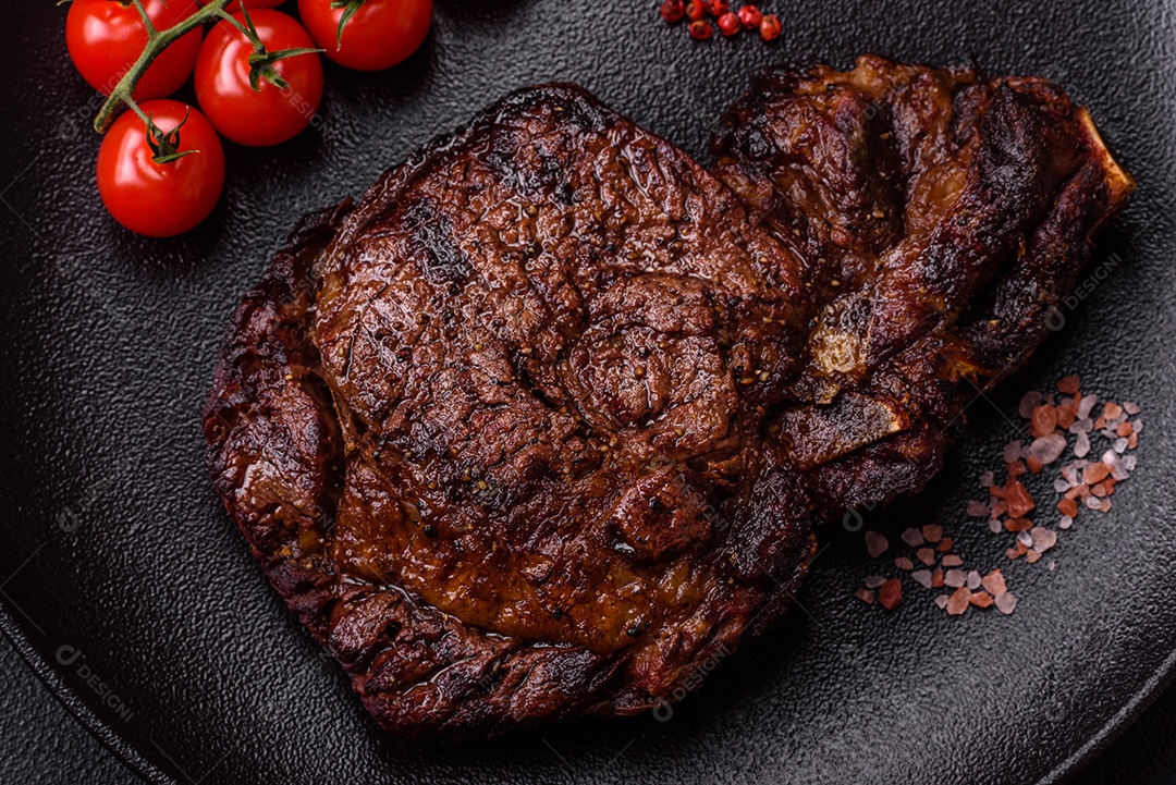 Delicioso bife suculento de lombo grelhado com sal, especiarias e ervas em um fundo escuro de concreto