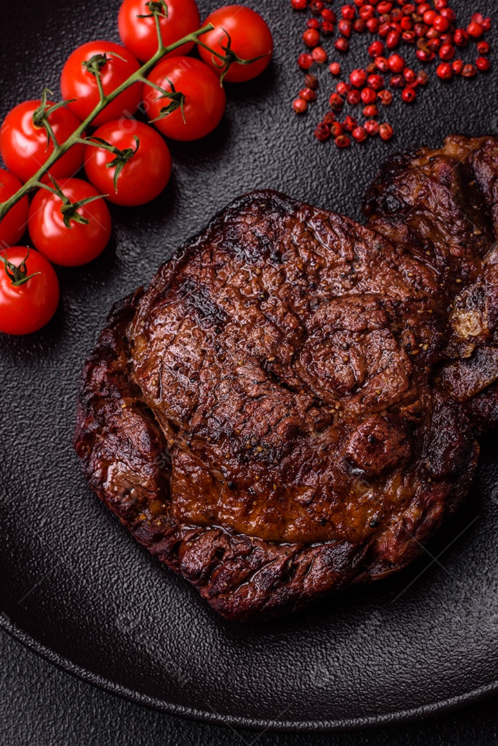 Delicioso bife suculento de lombo grelhado com sal, especiarias e ervas em um fundo escuro de concreto