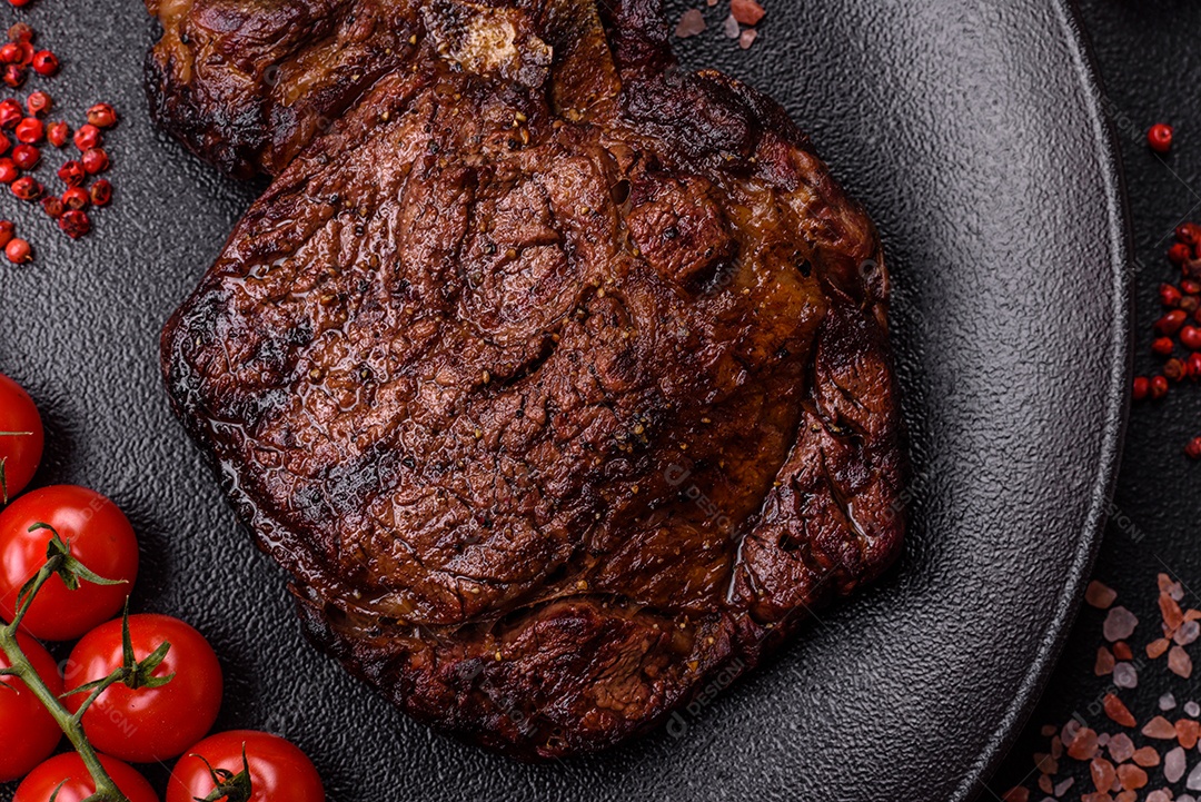 Delicioso bife suculento de lombo grelhado com sal, especiarias e ervas em um fundo escuro de concreto