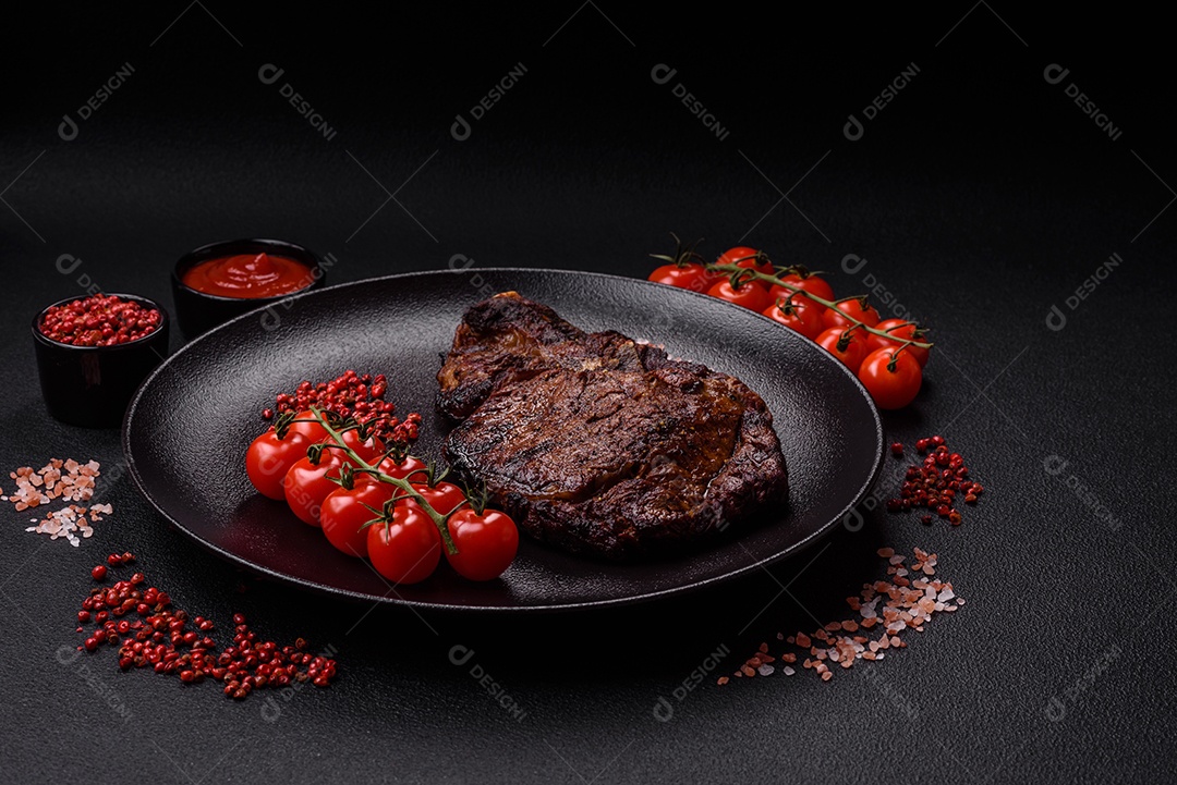 Delicioso bife suculento de lombo grelhado com sal, especiarias e ervas em um fundo escuro de concreto