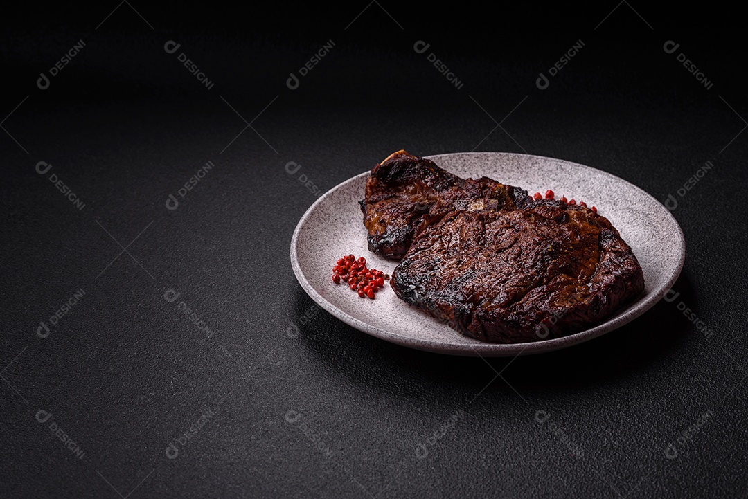 Delicioso bife suculento de lombo grelhado com sal, especiarias e ervas em um fundo escuro de concreto