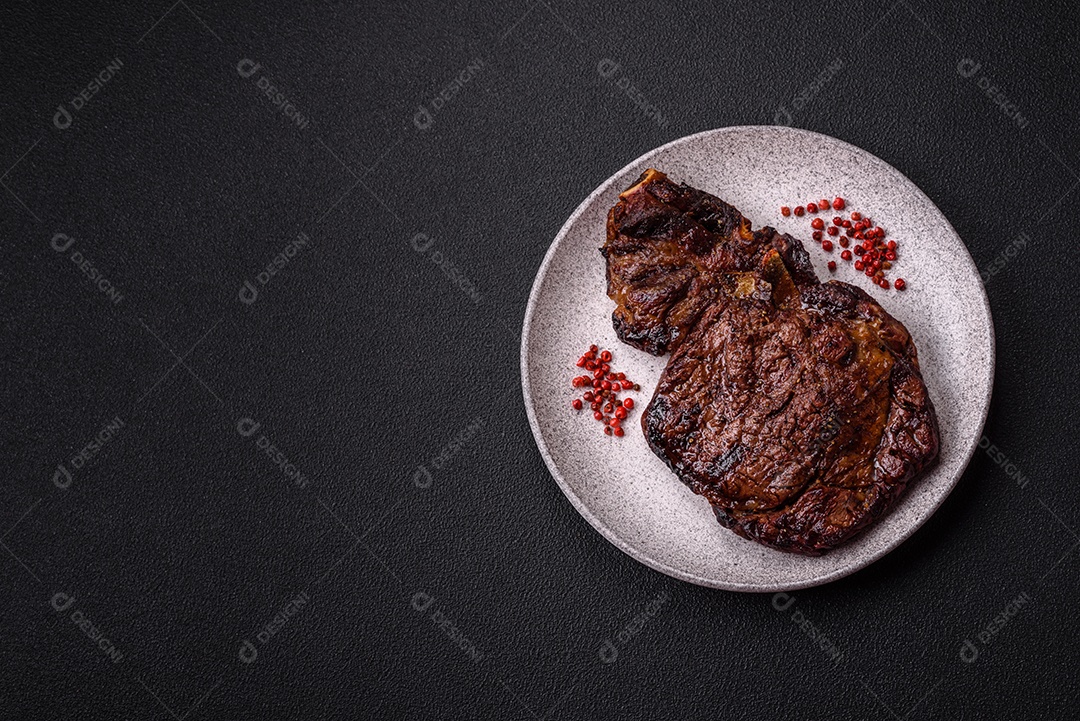 Delicioso bife suculento de lombo grelhado com sal, especiarias e ervas em um fundo escuro de concreto