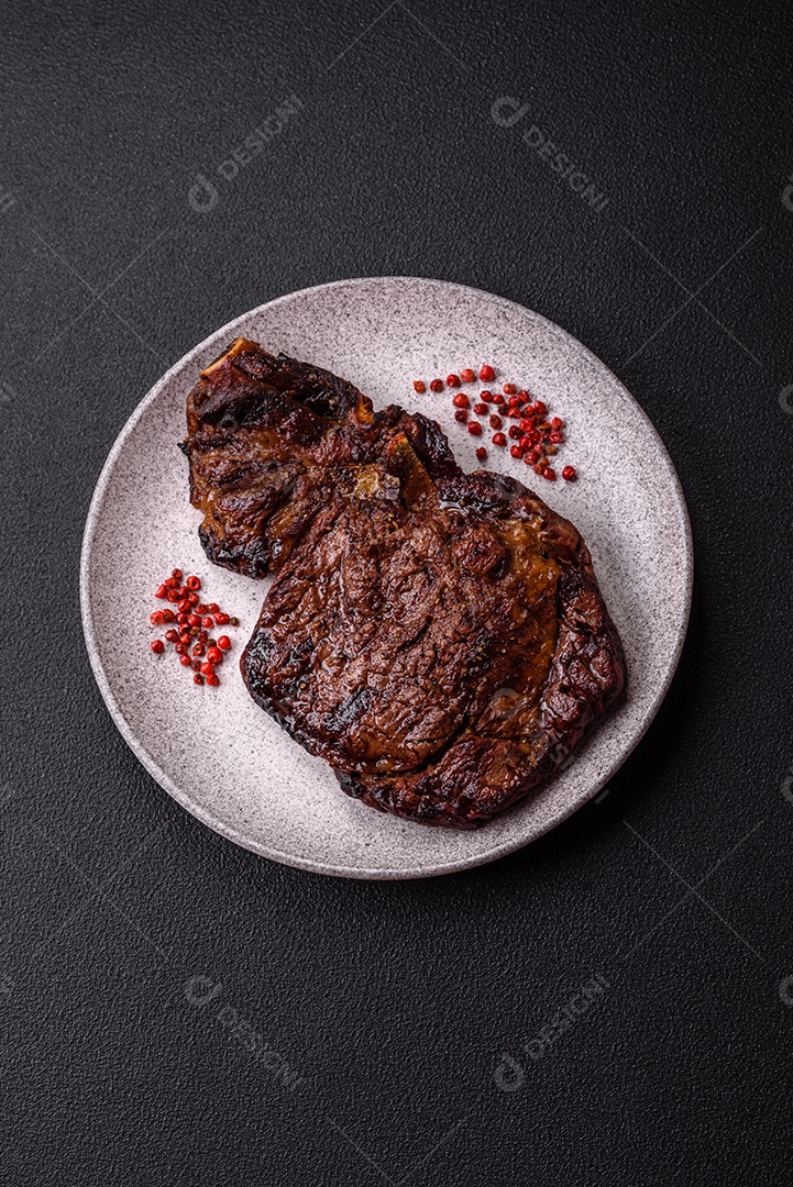 Delicioso bife suculento de lombo grelhado com sal, especiarias e ervas em um fundo escuro de concreto