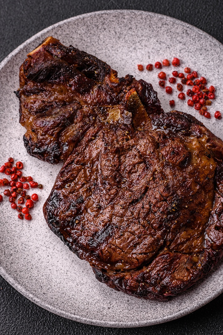 Delicioso bife suculento de lombo grelhado com sal, especiarias e ervas em um fundo escuro de concreto
