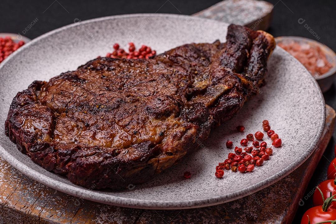 Delicioso bife suculento de lombo grelhado com sal, especiarias e ervas em um fundo escuro de concreto