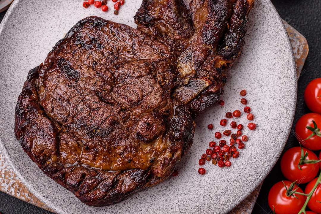 Delicioso bife suculento de lombo grelhado com sal, especiarias e ervas em um fundo escuro de concreto