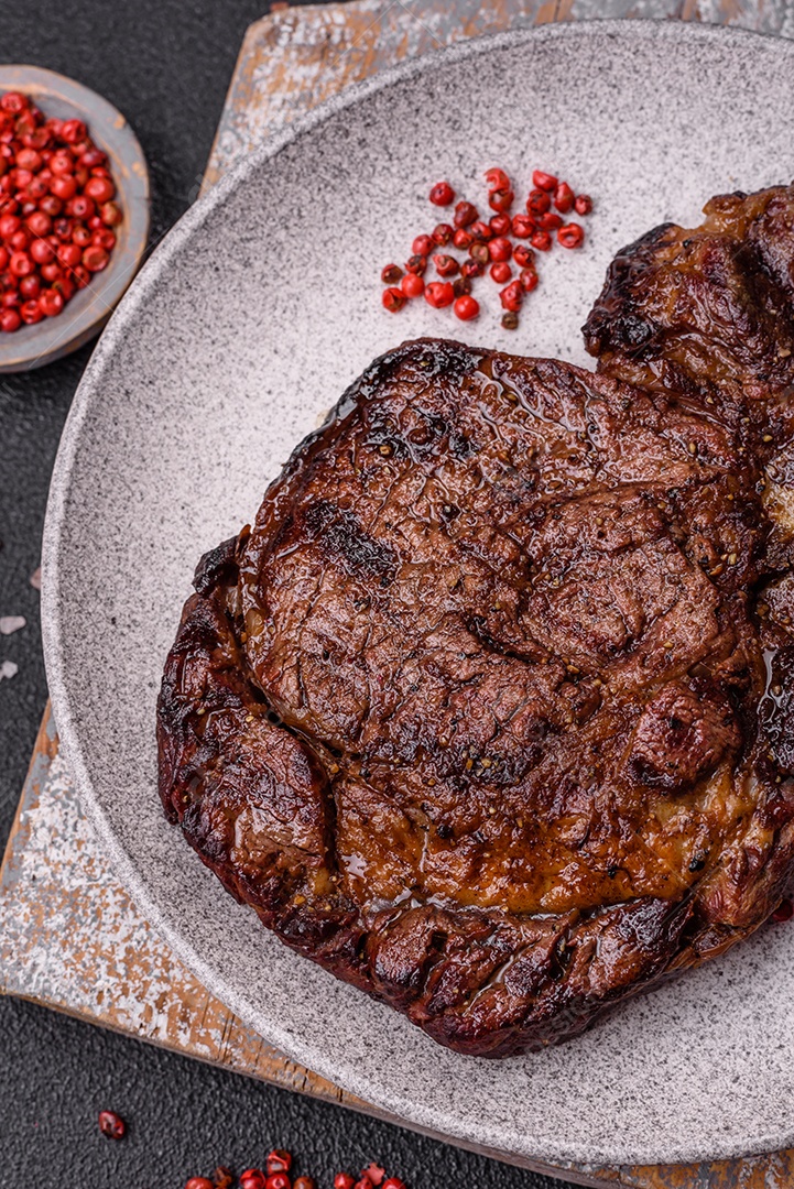 Delicioso bife suculento de lombo grelhado com sal, especiarias e ervas em um fundo escuro de concreto