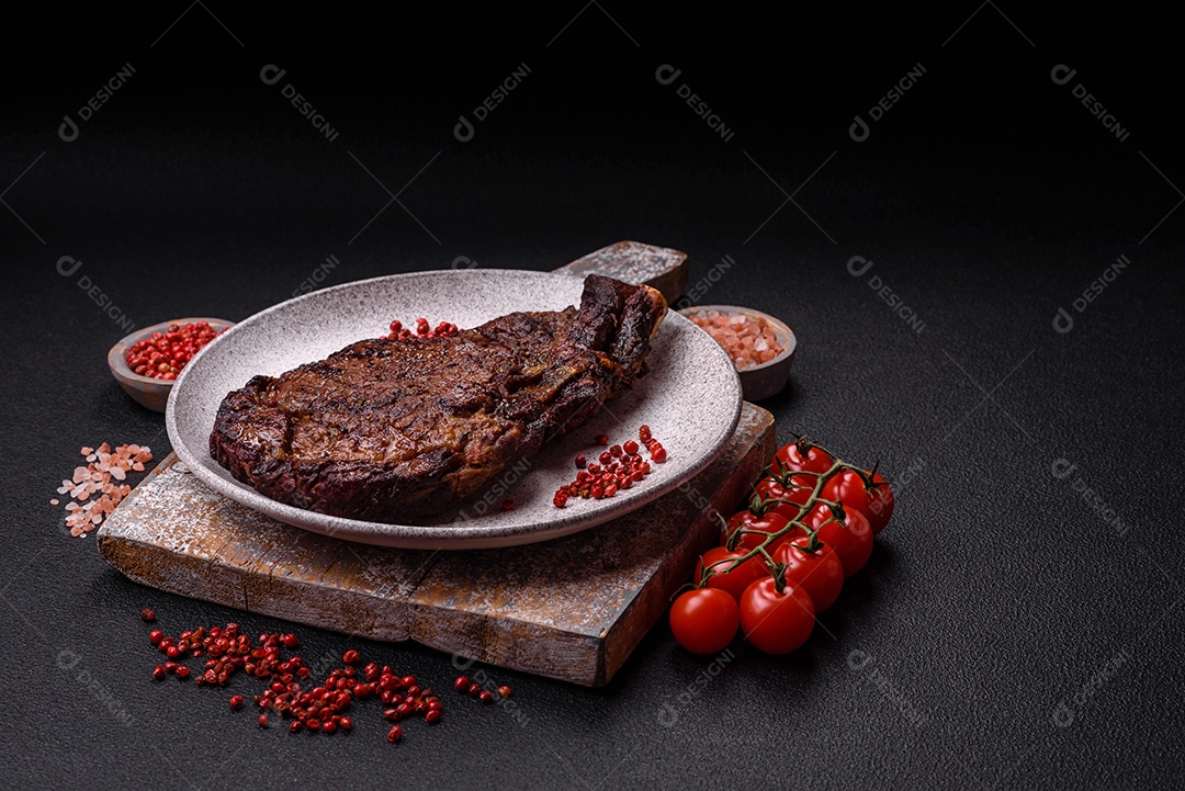 Delicioso bife suculento de lombo grelhado com sal, especiarias e ervas em um fundo escuro de concreto