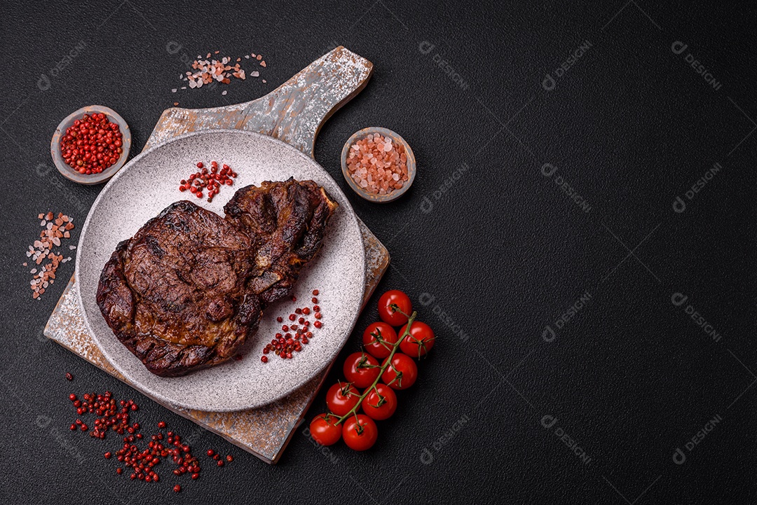 Delicioso bife suculento de lombo grelhado com sal, especiarias e ervas em um fundo escuro de concreto