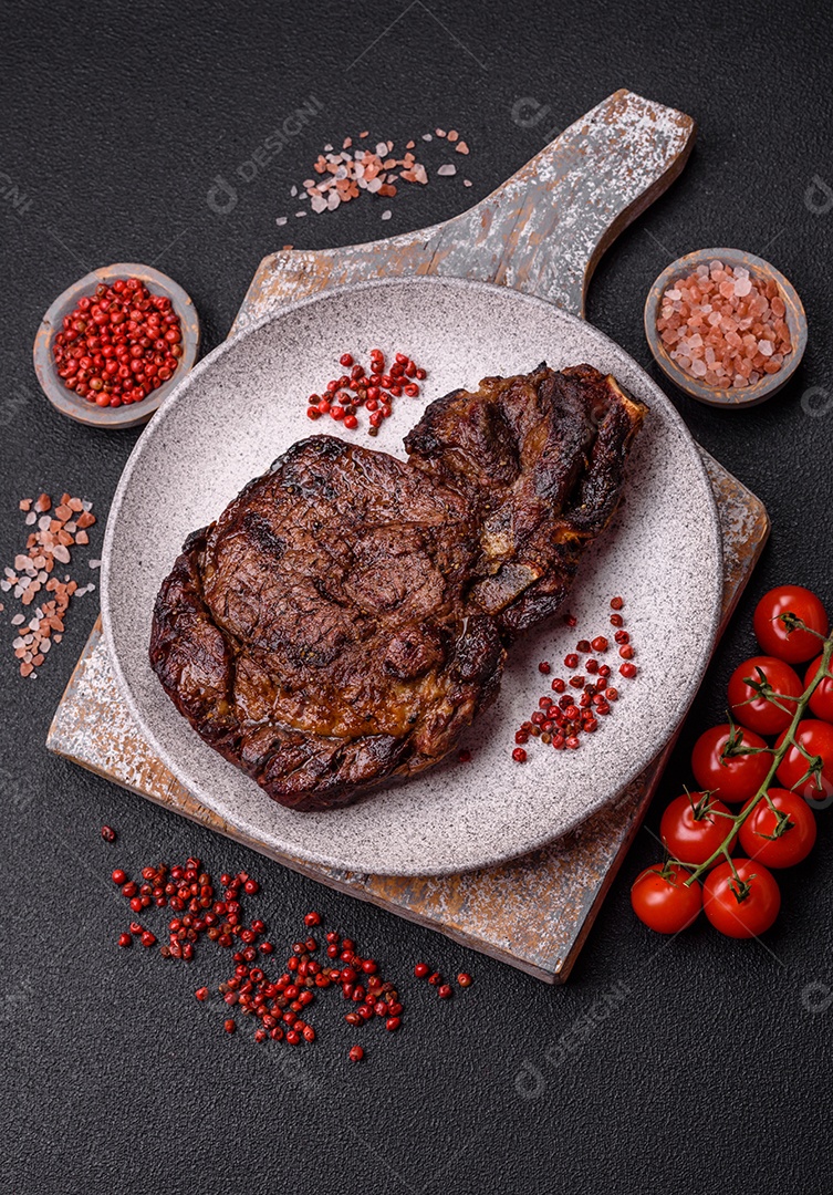 Delicioso bife suculento de lombo grelhado com sal, especiarias e ervas em um fundo escuro de concreto