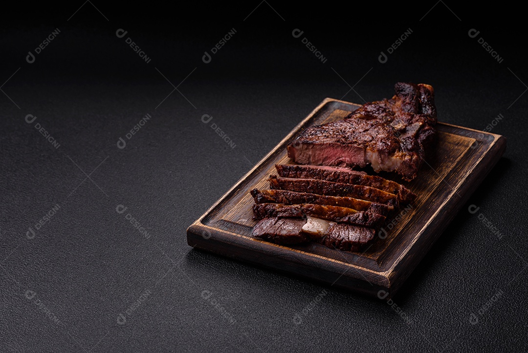 Delicioso bife suculento de lombo grelhado com sal, especiarias e ervas em um fundo escuro de concreto