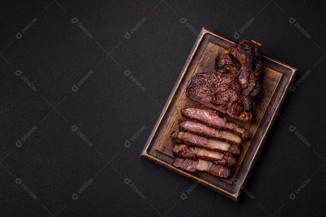 Delicioso bife suculento de lombo grelhado com sal, especiarias e ervas em um fundo escuro de concreto