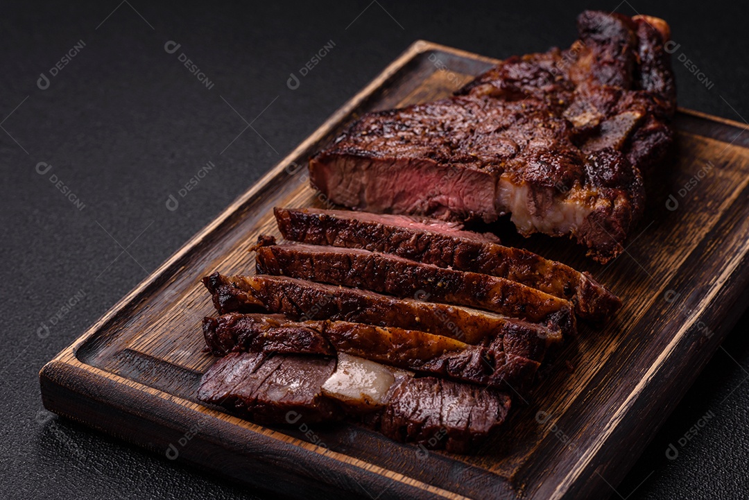 Delicioso bife suculento de lombo grelhado com sal, especiarias e ervas em um fundo escuro de concreto