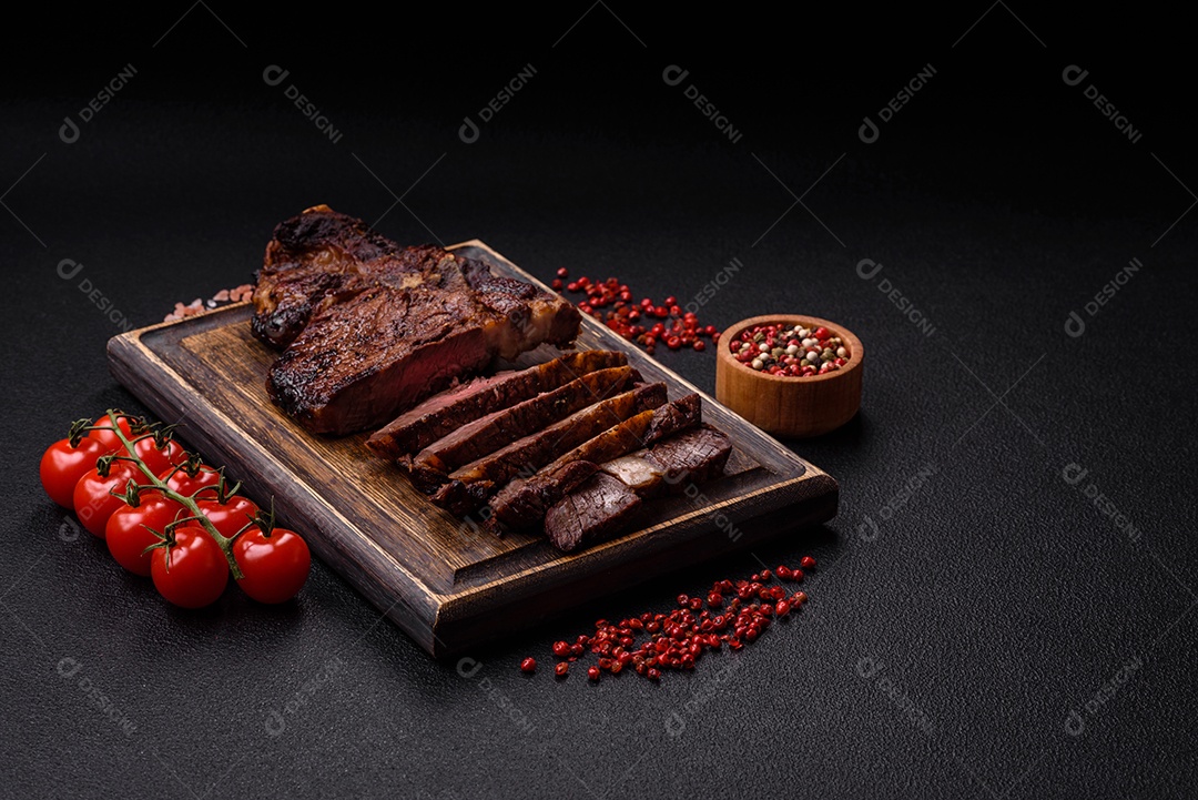 Delicioso bife suculento de lombo grelhado com sal, especiarias e ervas em um fundo escuro de concreto