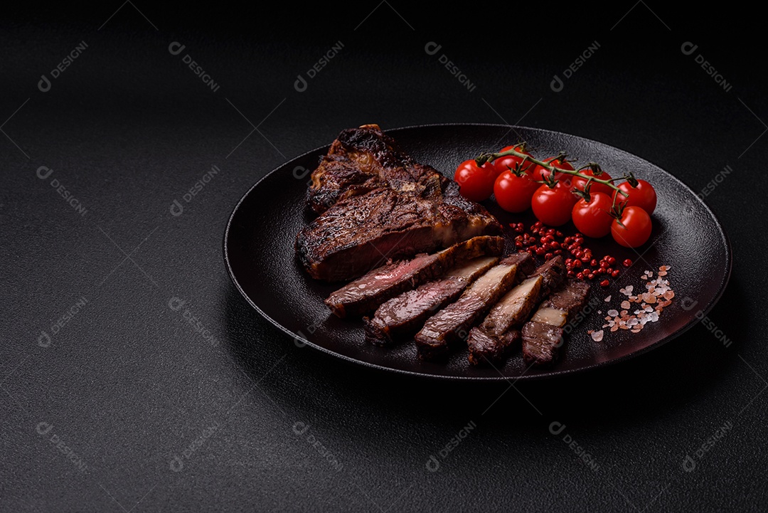 Delicioso bife suculento de lombo grelhado com sal, especiarias e ervas em um fundo escuro de concreto