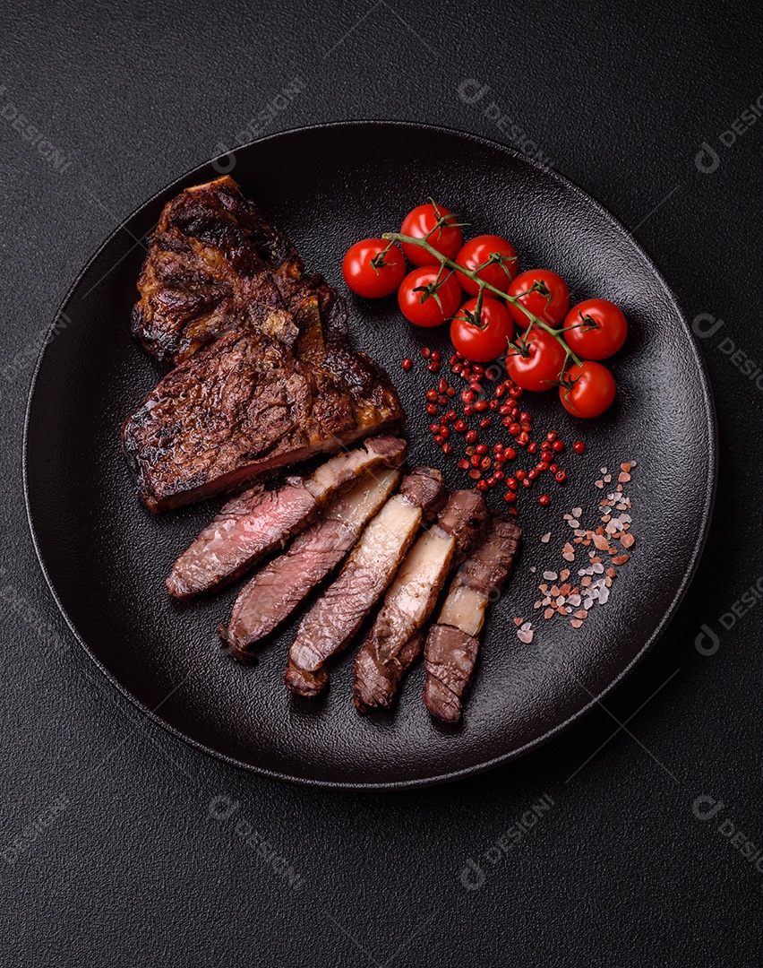 Delicioso bife suculento de lombo grelhado com sal, especiarias e ervas em um fundo escuro de concreto