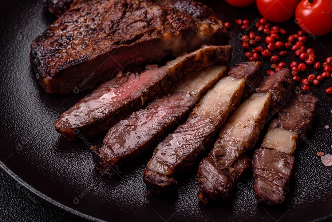 Delicioso bife suculento de lombo grelhado com sal, especiarias e ervas em um fundo escuro de concreto