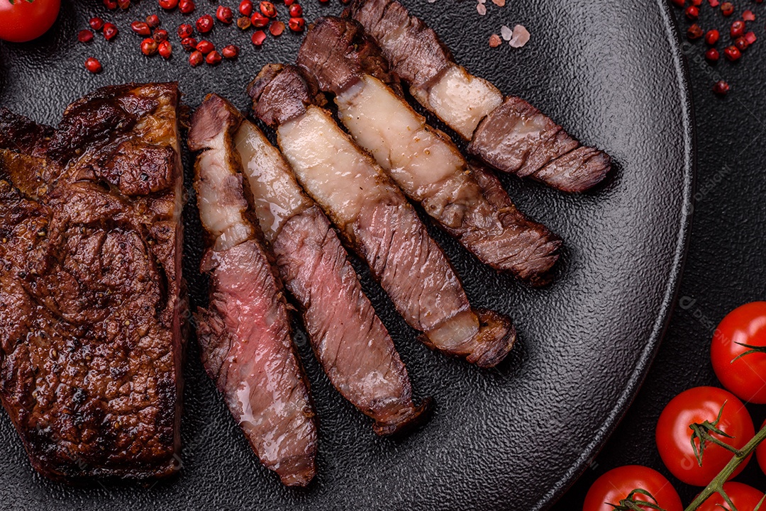 Delicioso bife suculento de lombo grelhado com sal, especiarias e ervas em um fundo escuro de concreto