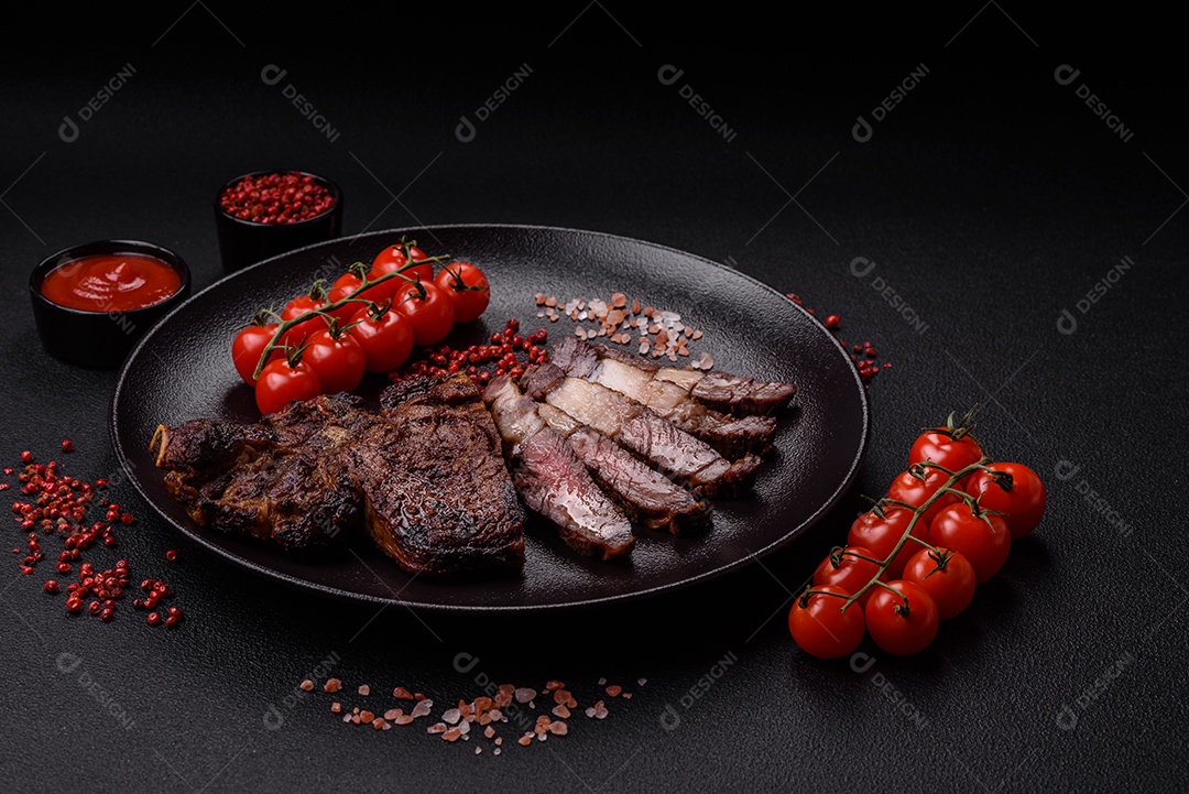 Delicioso bife suculento de lombo grelhado com sal, especiarias e ervas em um fundo escuro de concreto