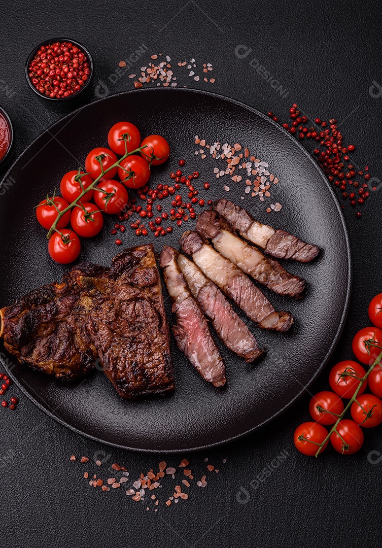 Delicioso bife suculento de lombo grelhado com sal, especiarias e ervas em um fundo escuro de concreto