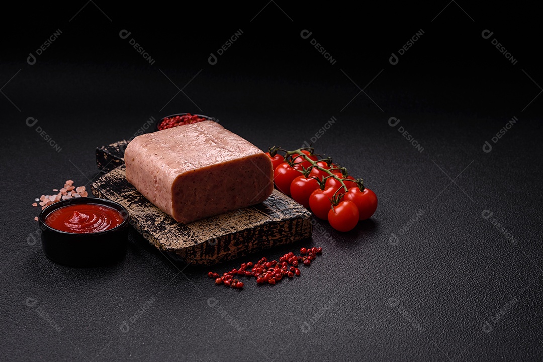 Delicioso presunto rosa enlatado com sal, especiarias e ervas sobre um fundo escuro de concreto