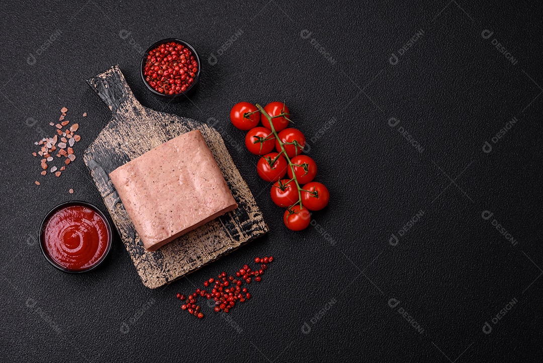 Delicioso presunto rosa enlatado com sal, especiarias e ervas sobre um fundo escuro de concreto