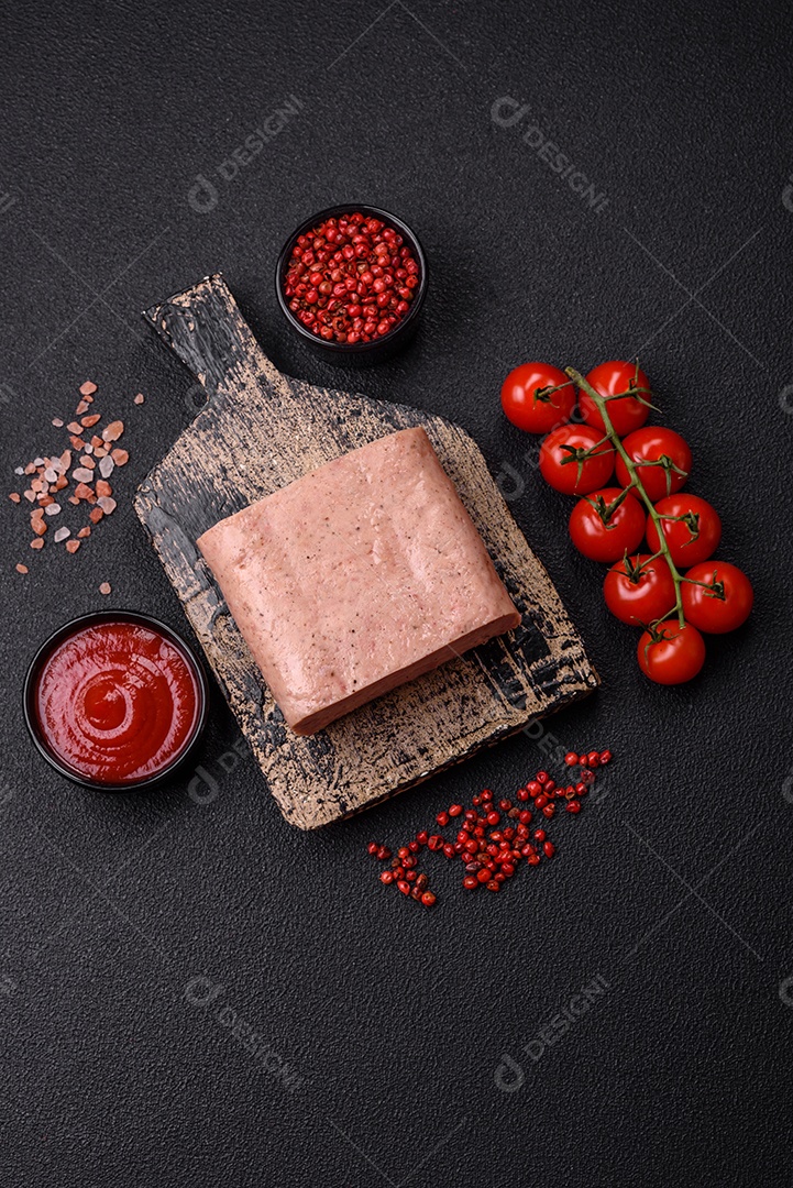 Delicioso presunto rosa enlatado com sal, especiarias e ervas sobre um fundo escuro de concreto