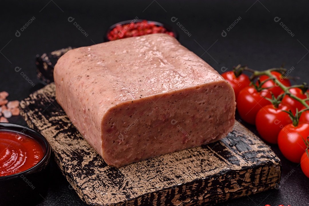 Delicioso presunto rosa enlatado com sal, especiarias e ervas sobre um fundo escuro de concreto