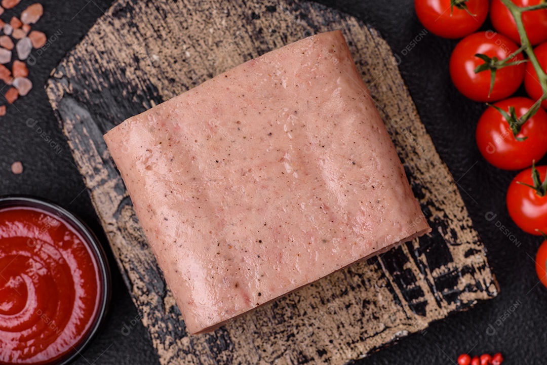 Delicioso presunto rosa enlatado com sal, especiarias e ervas sobre um fundo escuro de concreto