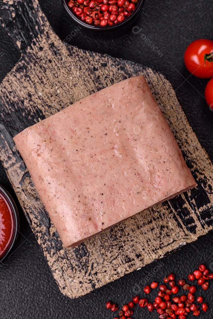 Delicioso presunto rosa enlatado com sal, especiarias e ervas sobre um fundo escuro de concreto