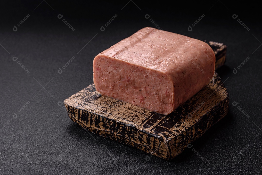 Delicioso presunto rosa enlatado com sal, especiarias e ervas sobre um fundo escuro de concreto