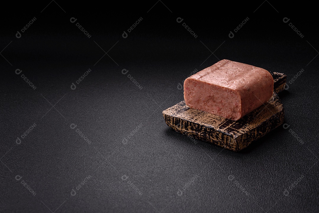 Delicioso presunto rosa enlatado com sal, especiarias e ervas sobre um fundo escuro de concreto