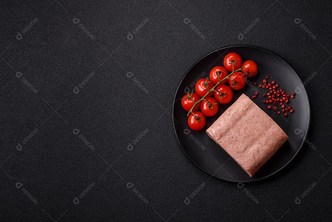 Delicioso presunto rosa enlatado com sal, especiarias e ervas sobre um fundo escuro de concreto