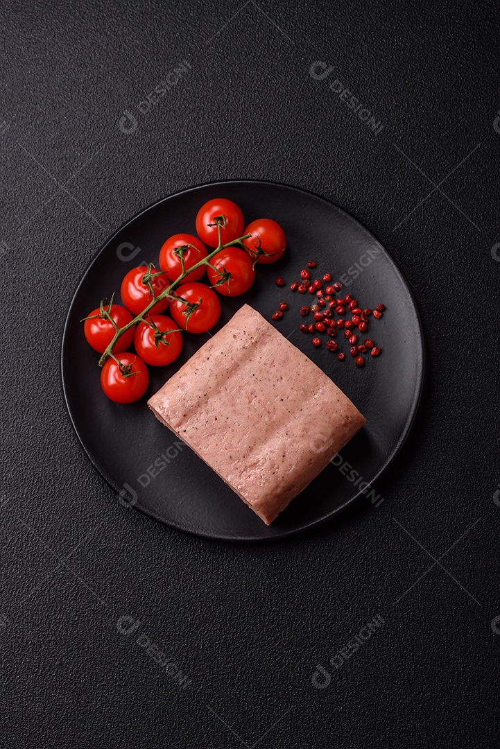 Delicioso presunto rosa enlatado com sal, especiarias e ervas sobre um fundo escuro de concreto