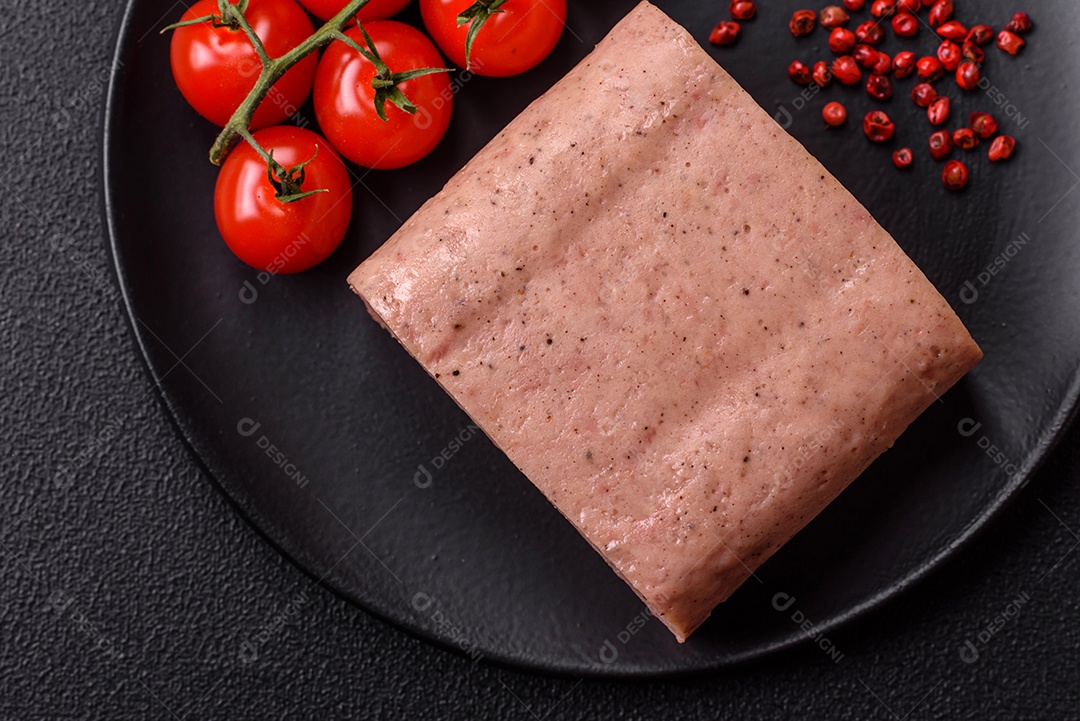 Delicioso presunto rosa enlatado com sal, especiarias e ervas sobre um fundo escuro de concreto