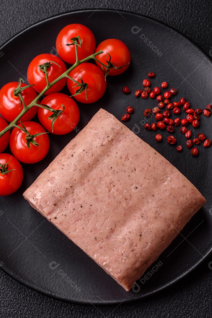 Delicioso presunto rosa enlatado com sal, especiarias e ervas sobre um fundo escuro de concreto