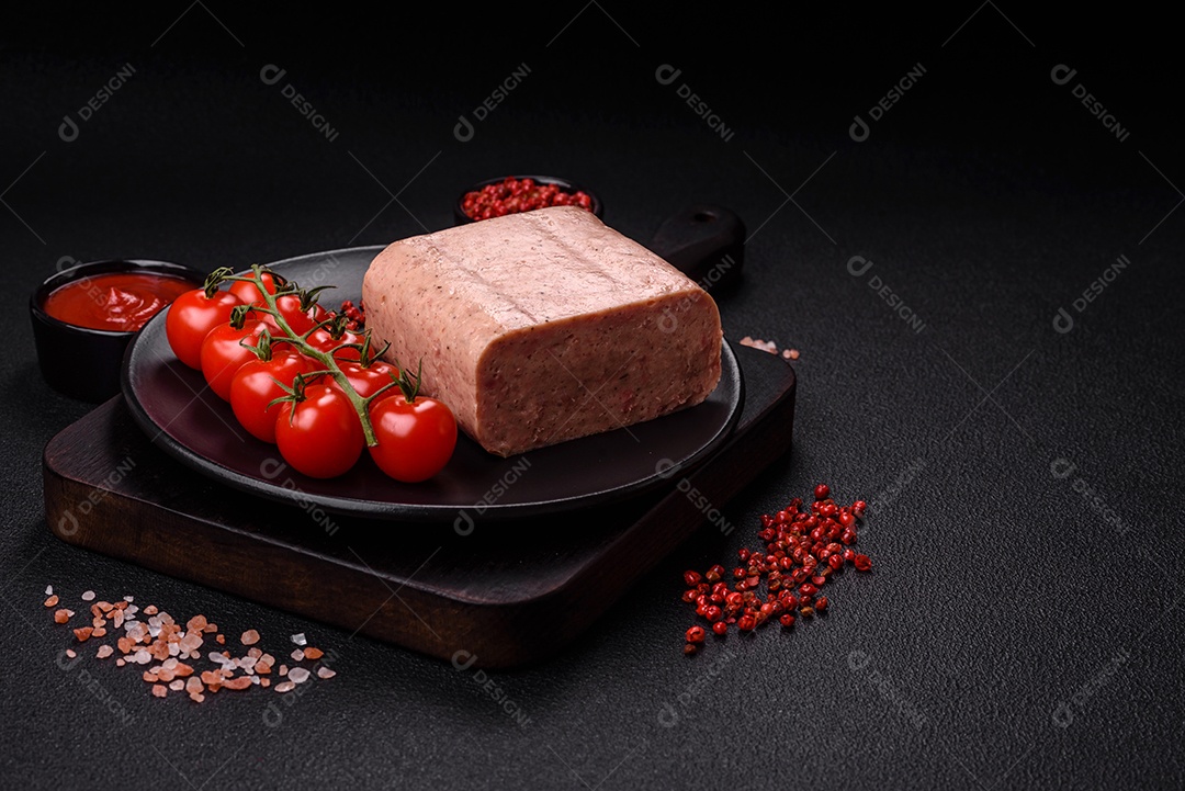 Delicioso presunto rosa enlatado com sal, especiarias e ervas sobre um fundo escuro de concreto