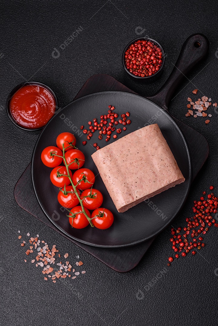 Delicioso presunto rosa enlatado com sal, especiarias e ervas sobre um fundo escuro de concreto